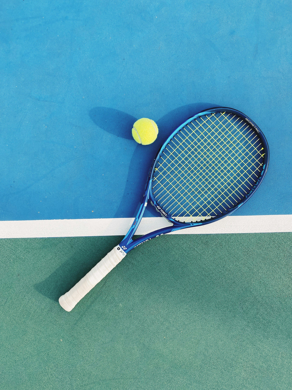 Strung racquet and ball on court at Tennis Lab FX